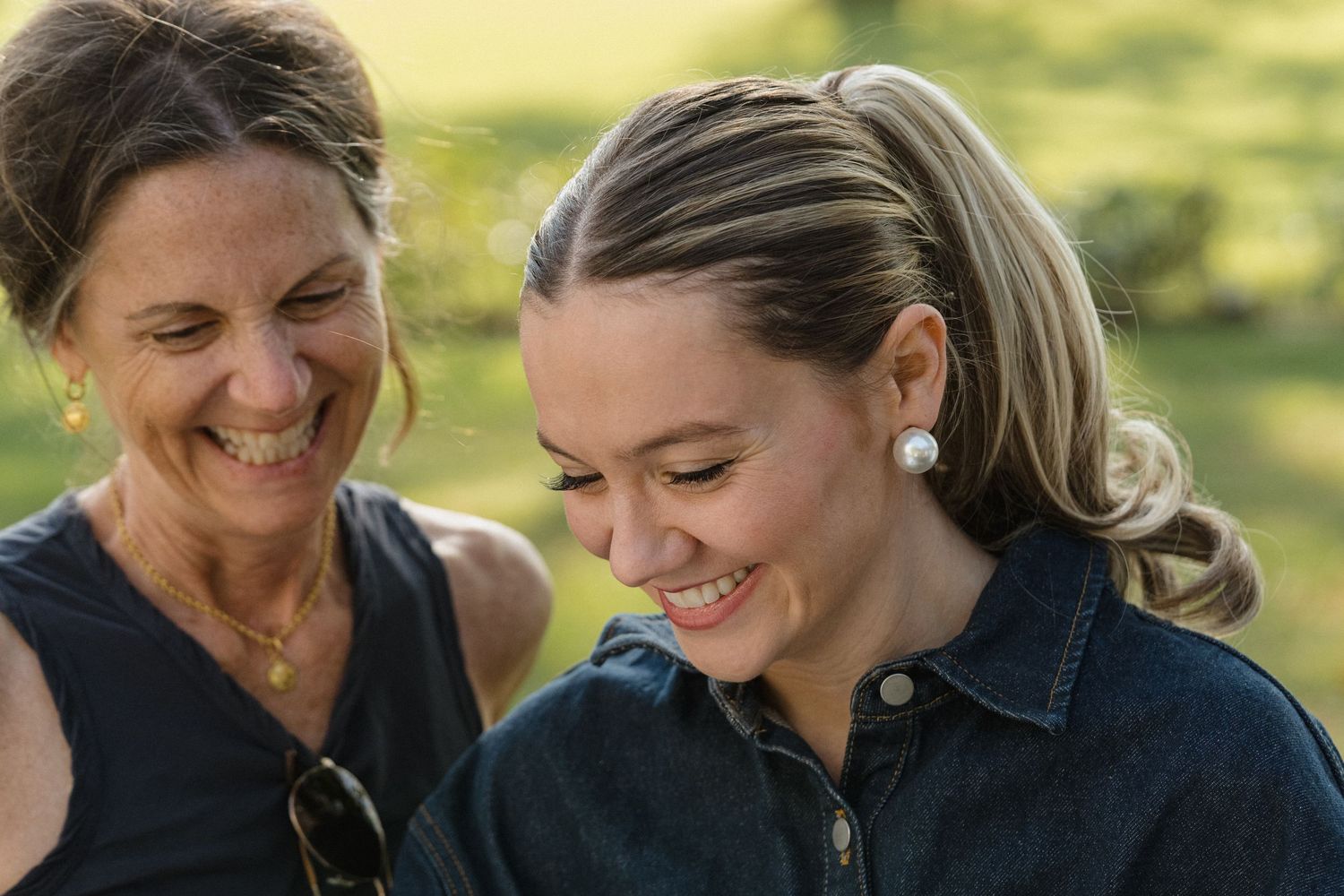 Two people sharing a joyful moment while looking at photographs together outdoors.