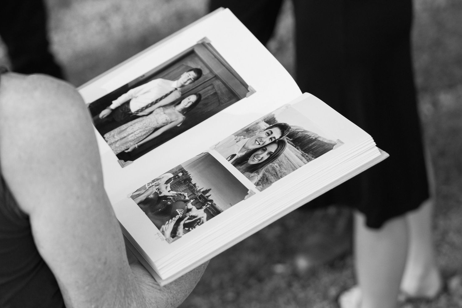 Black and white photo of an open album displaying vintage family photographs.