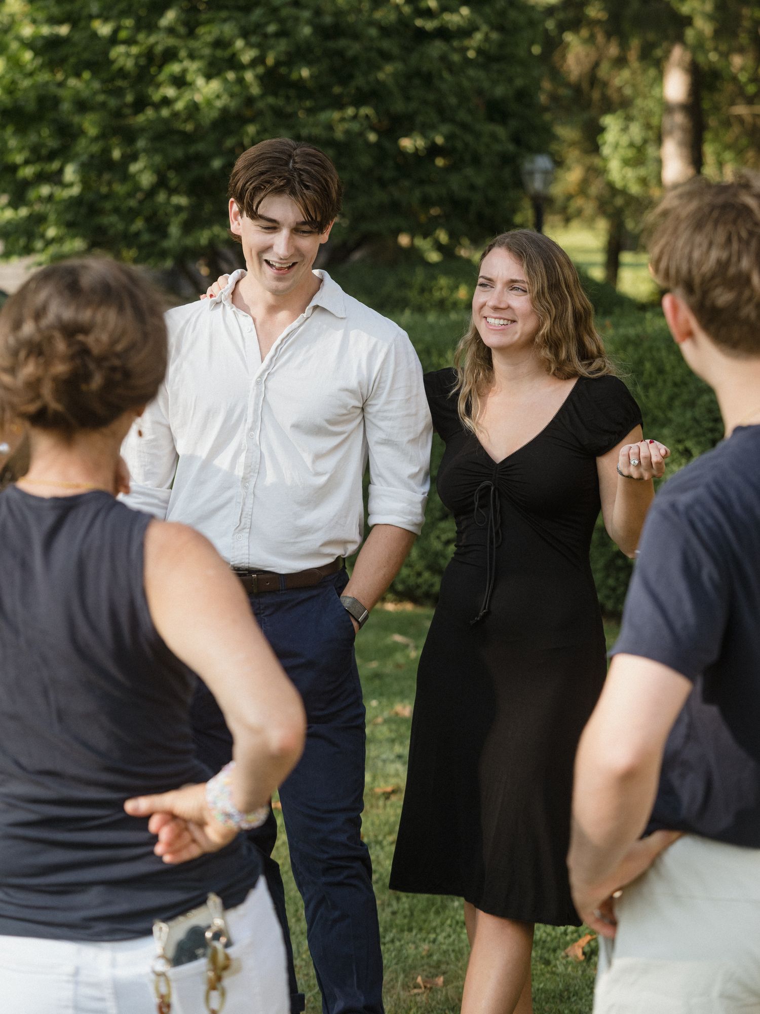 A group of people having an animated outdoor conversation on a grassy lawn.