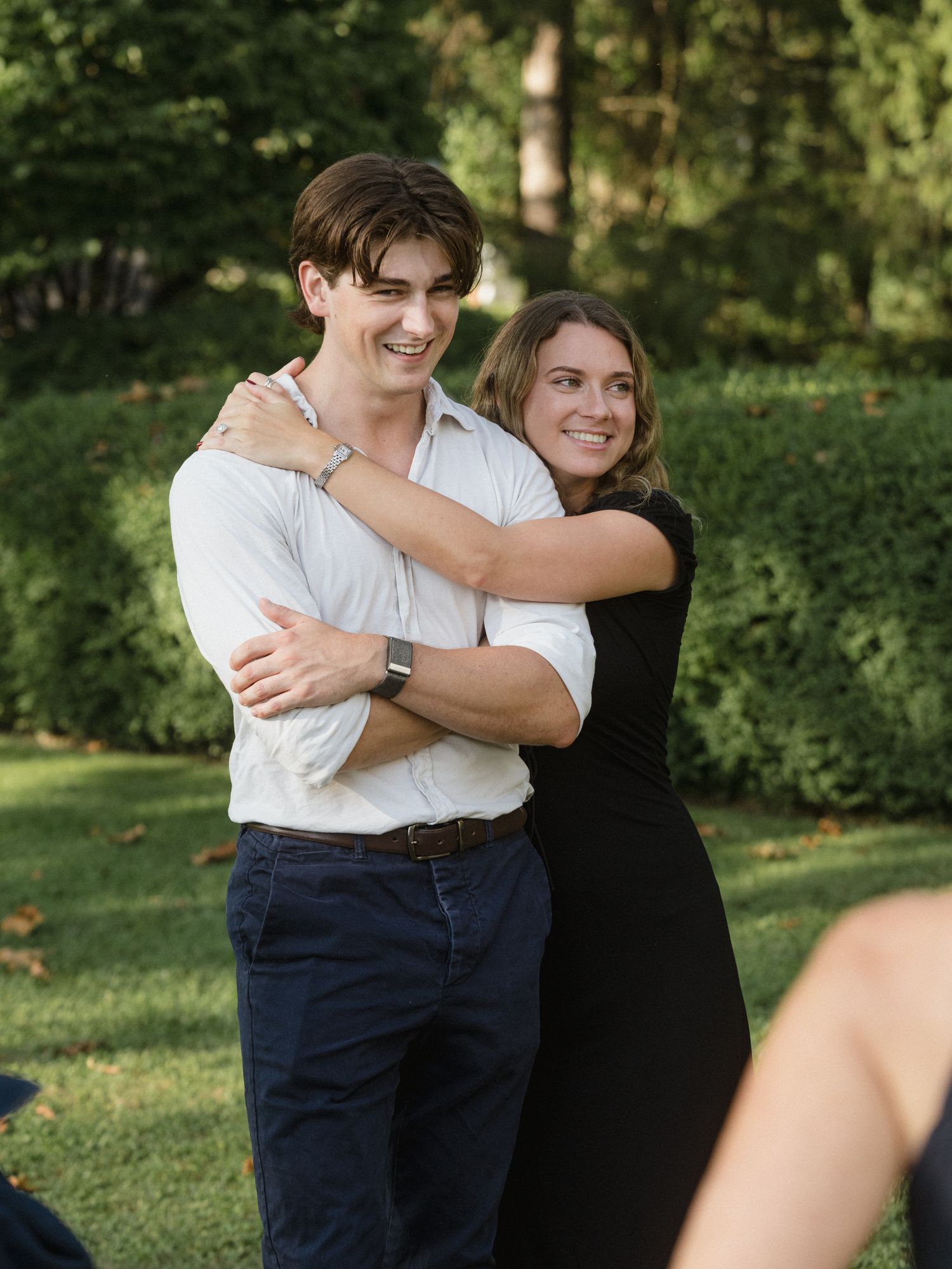 A couple shares an intimate embrace while standing together on a grassy lawn.