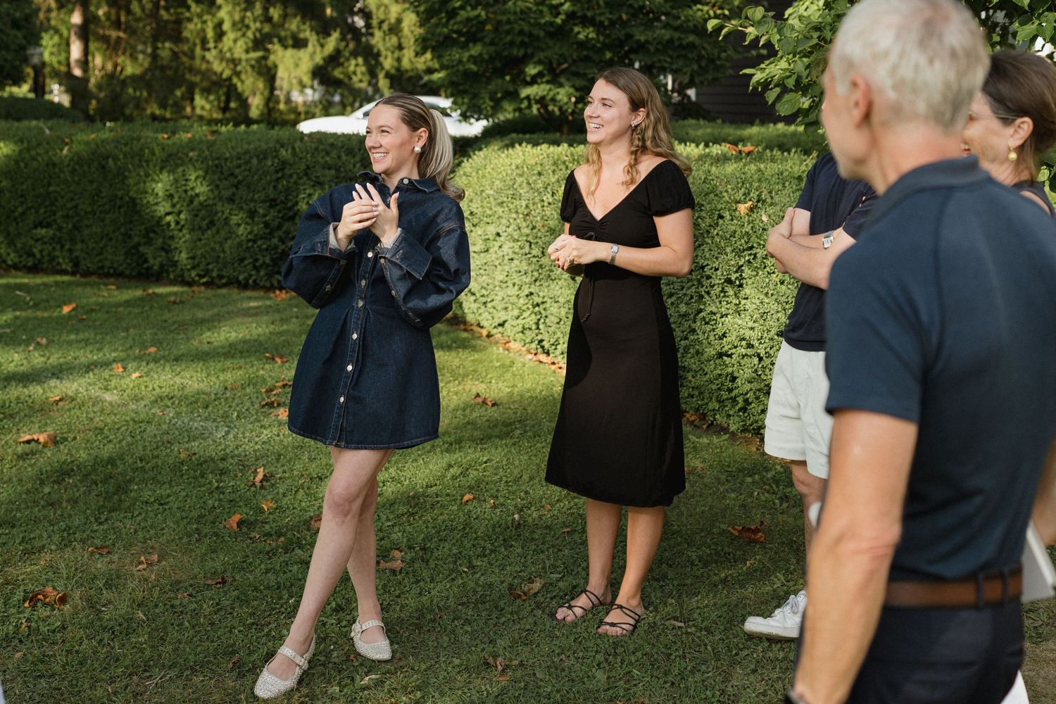 People engaged in casual conversation while standing in a backyard garden setting.