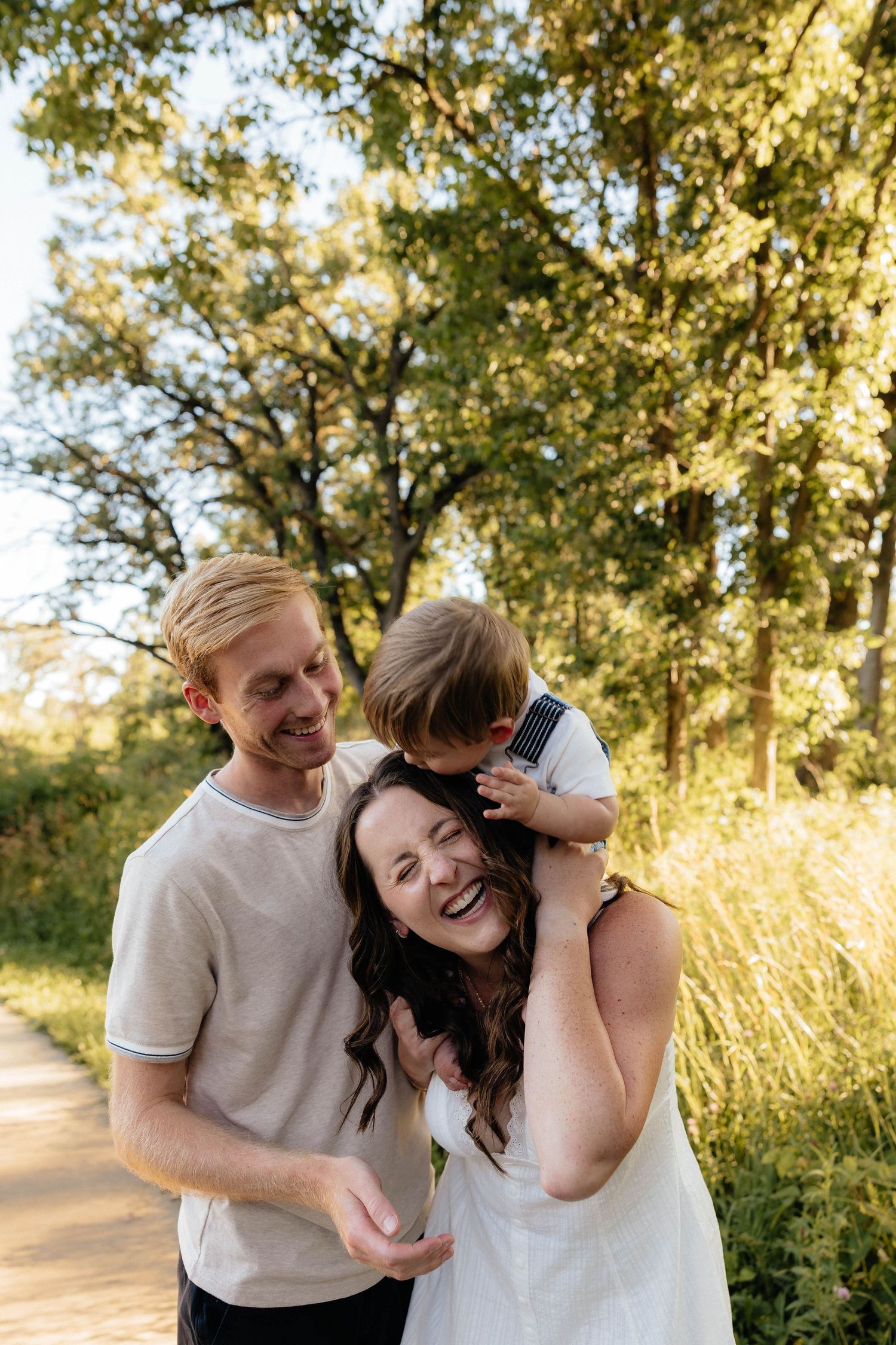 Family portrait in orchard with golden sunlight filtering through blossoming trees.