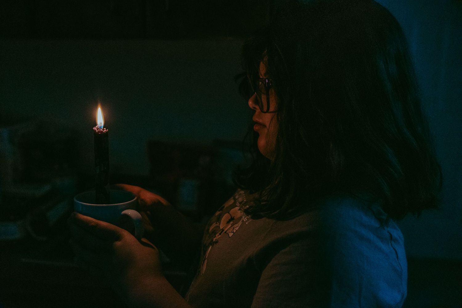 Child holding a candle in darkness, illuminated by warm candlelight in a moody, atmospheric setting.