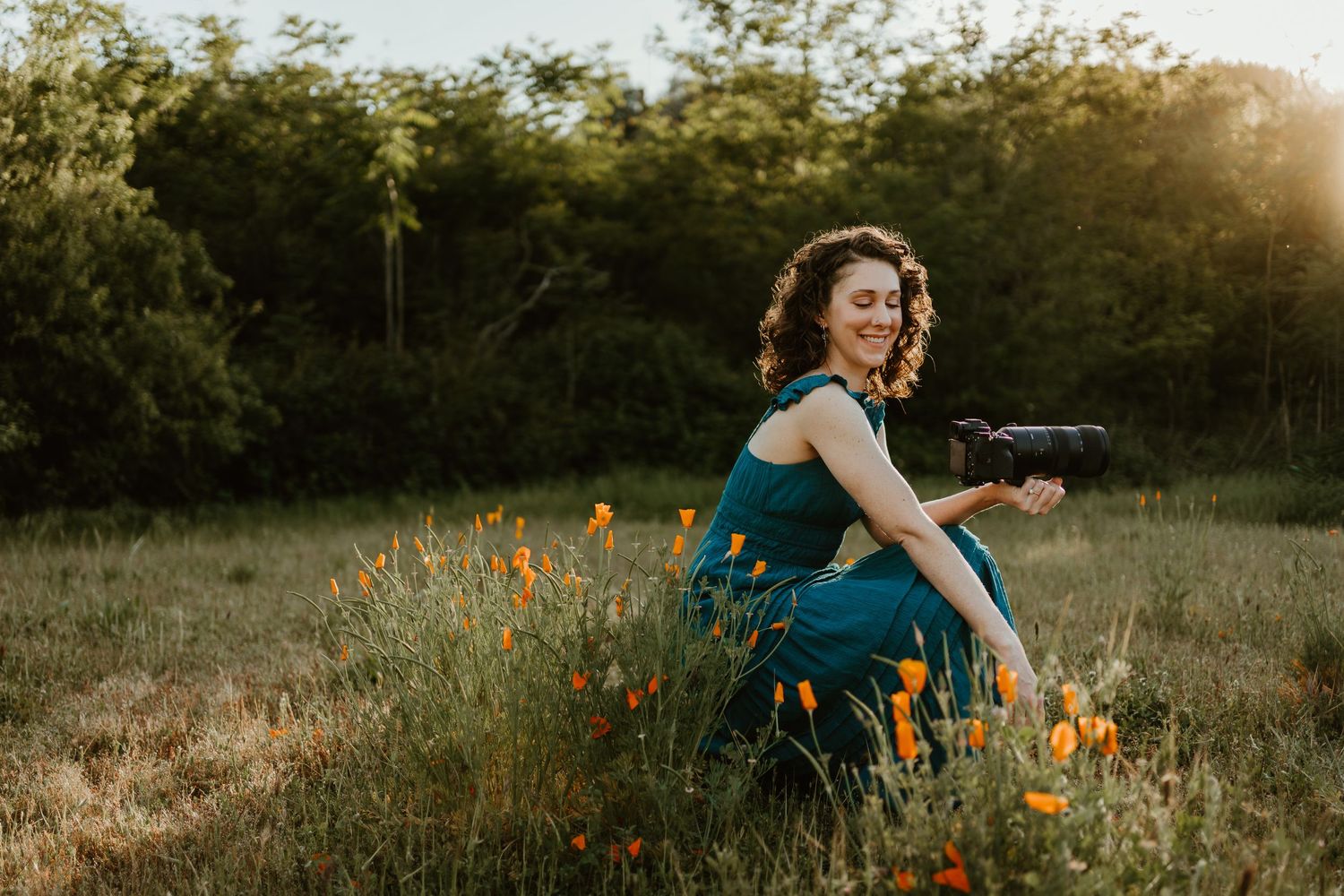 Black and white photo of a smiling woman holding a Sony camera, looking down at it with joy.