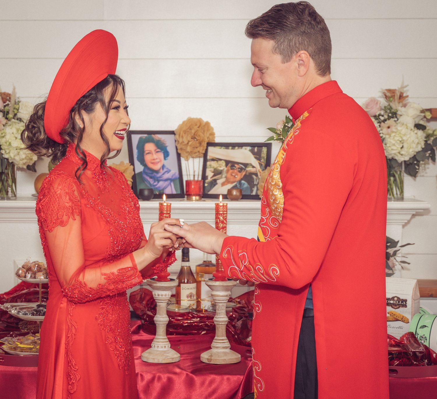 Couple in traditional Vietnamese red ao dai wedding attire exchanging rings at a ceremonial altar.