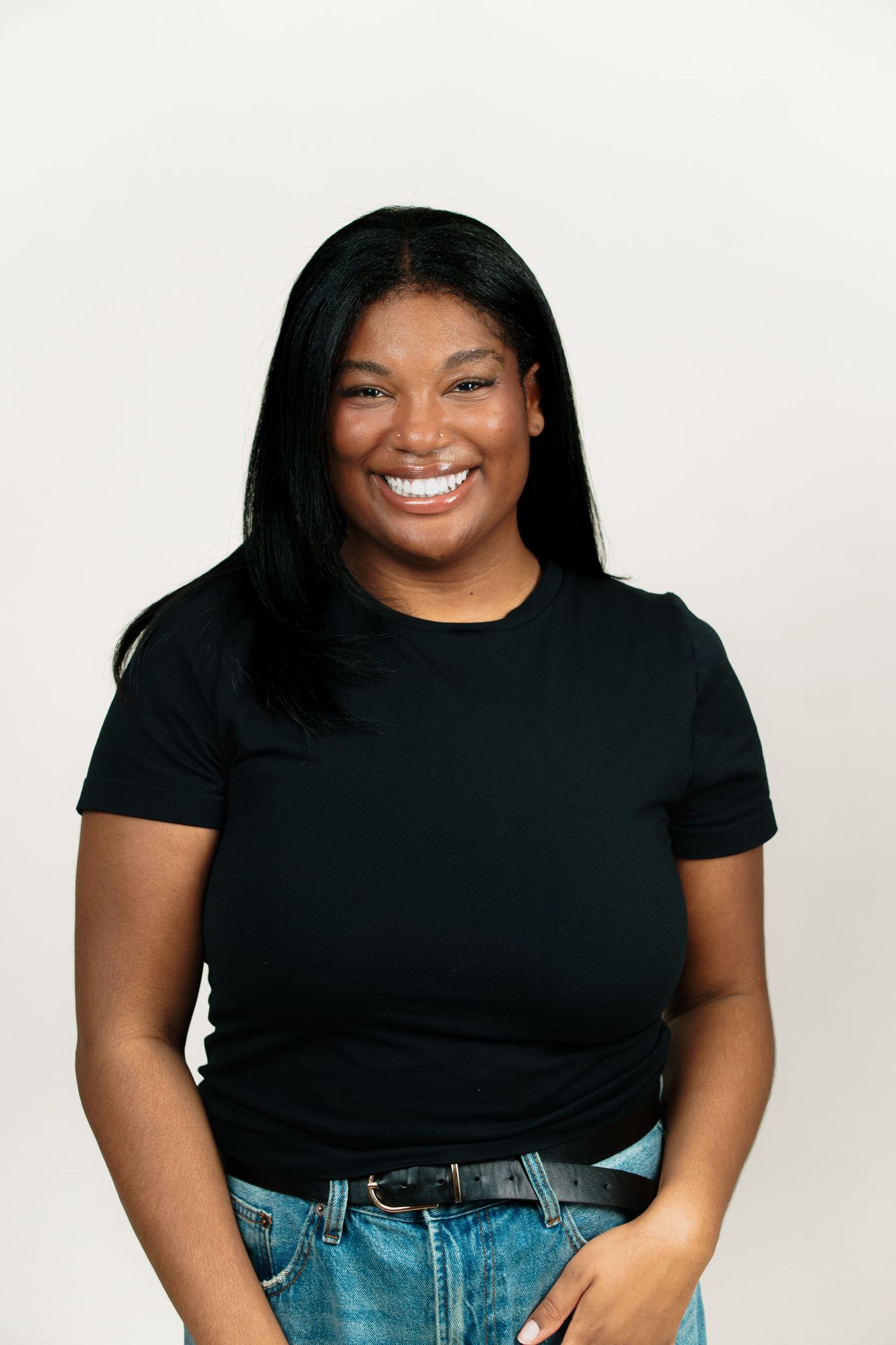 A person in a black t-shirt and blue jeans poses confidently against a white background in a photo series.