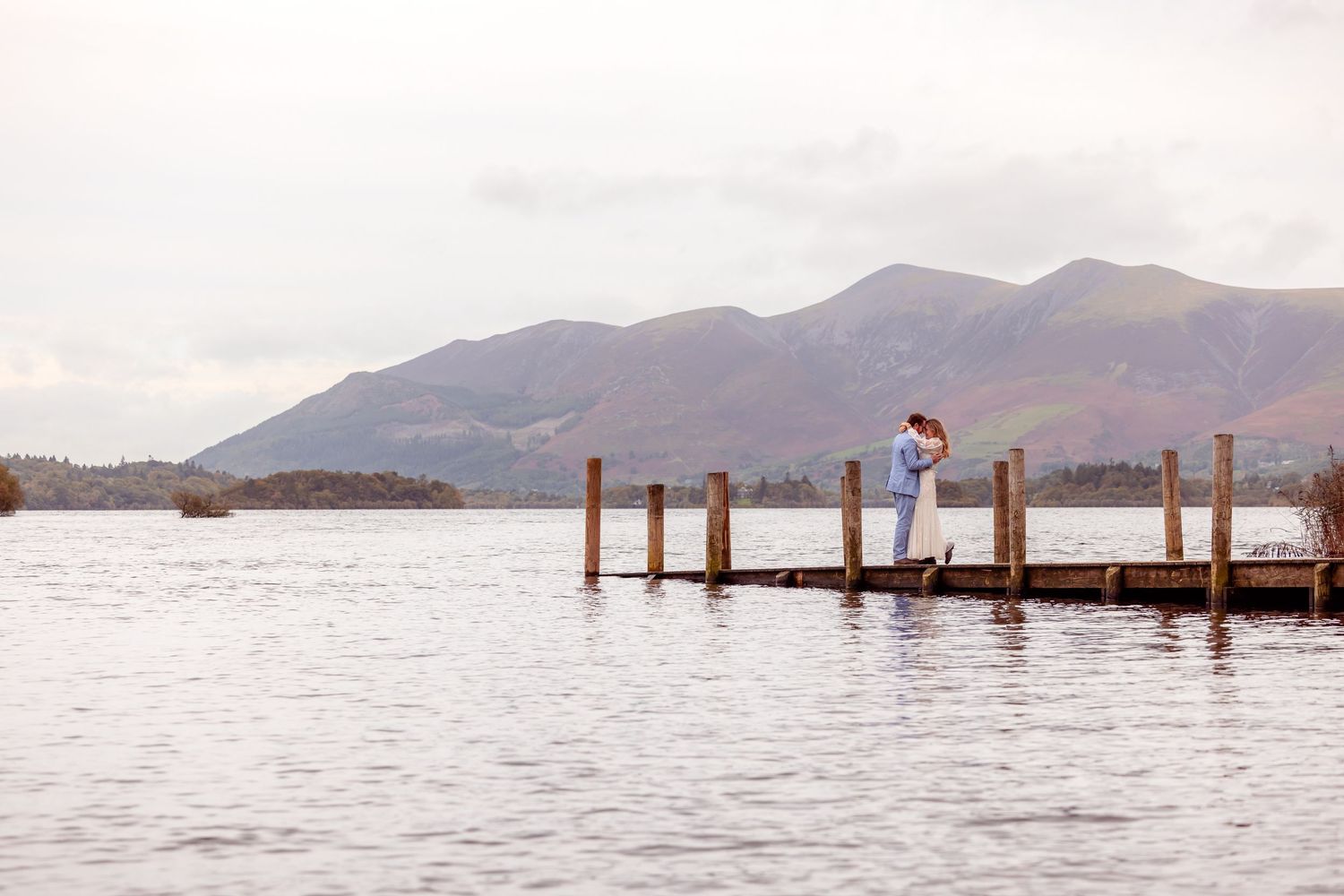 Couple embrace on the wooden jetty at Derwent Water - near Lodore Falls Hotel