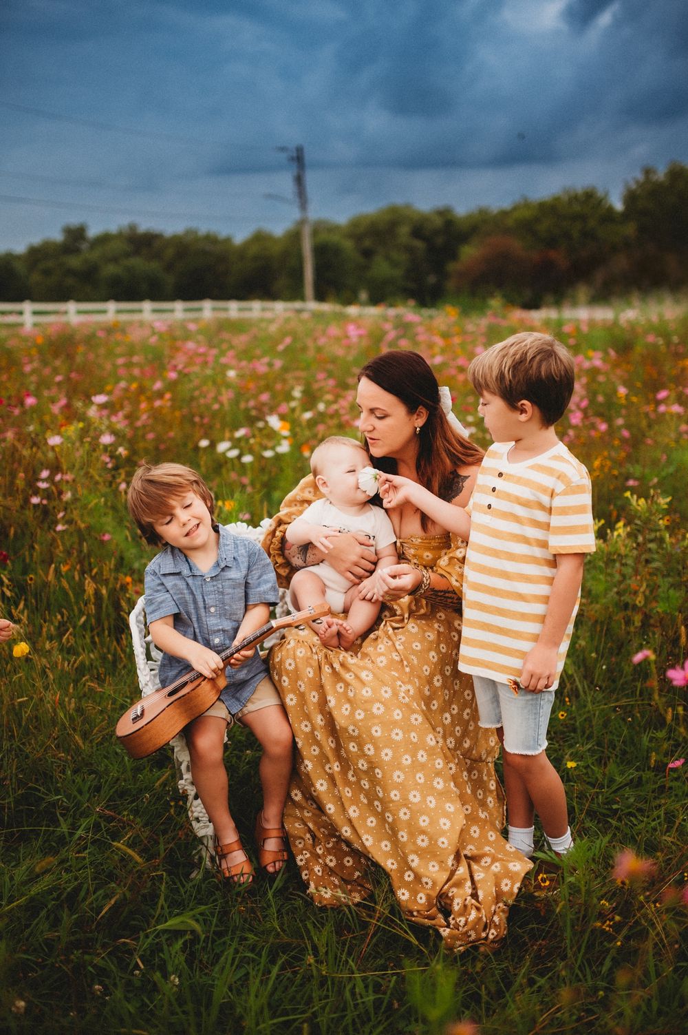 A family sits together in a wildflower field at sunset sharing playful moments among vibrant blooms.