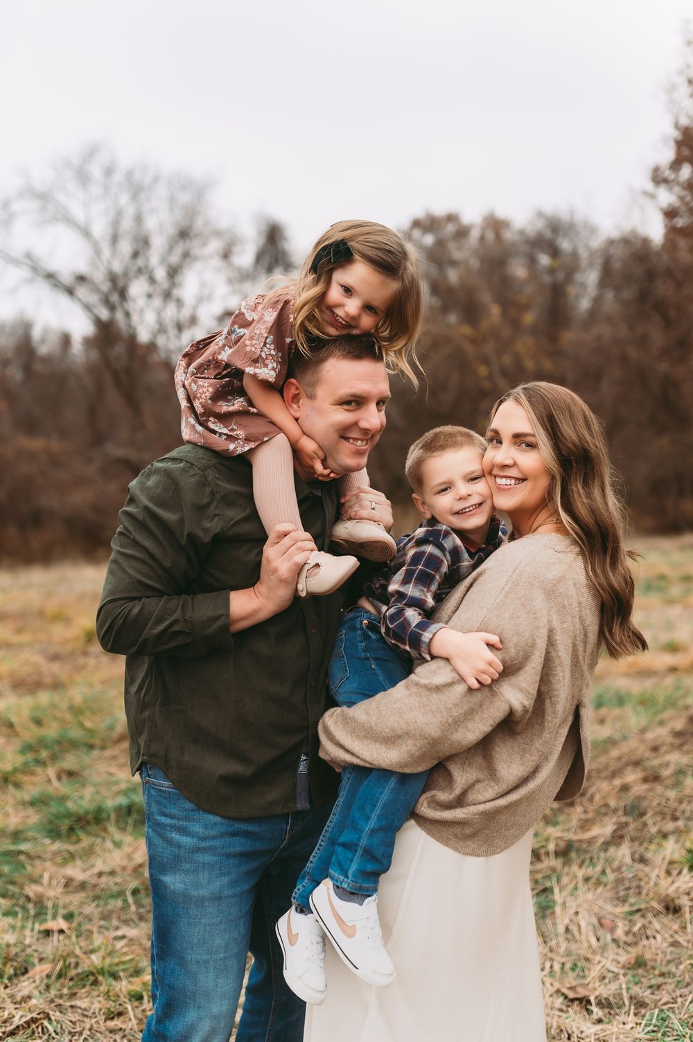 A joyful family shares tender moments together in a natural outdoor setting during autumn.