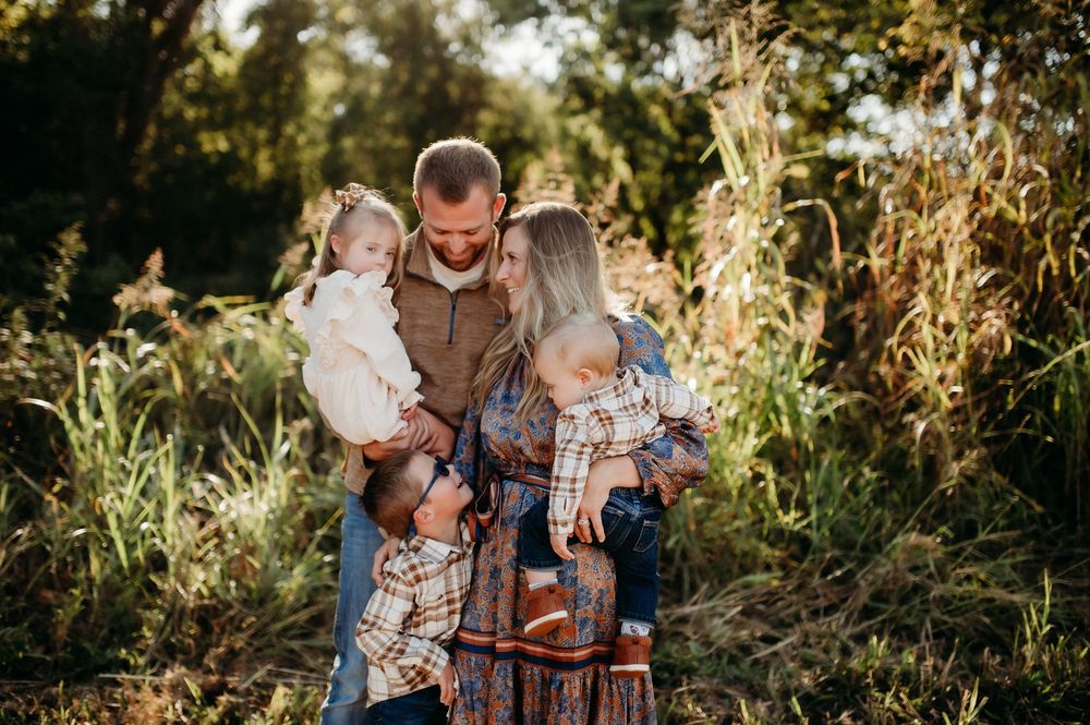 A family enjoys a tender moment together outdoors during golden hour in a natural setting.