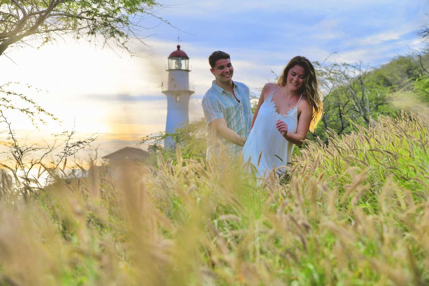 Photo session with engaged couple at Kualoa regional park in Oahu showing driftwood on sandy shores against tropical mountain backdrops.