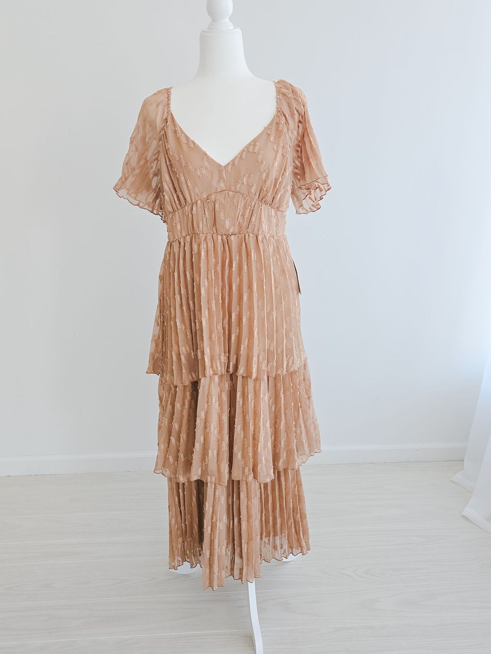 Romantic beige tiered maxi dress with flutter sleeves and empire waist displayed on white mannequin.