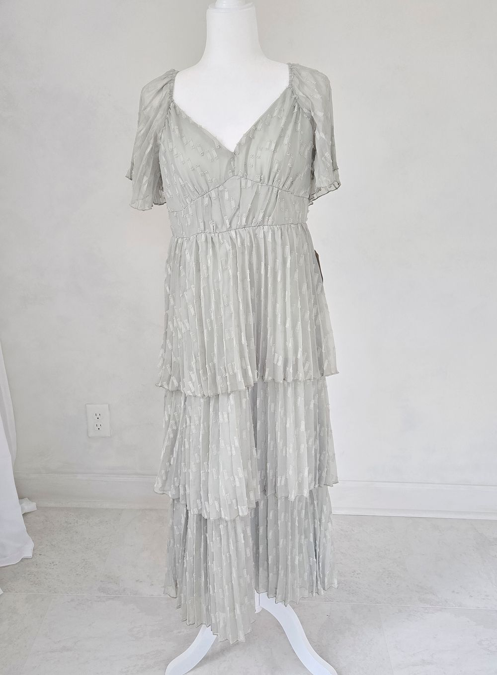 A light gray tiered maxi dress with short flutter sleeves and V-neckline displayed on a white mannequin.