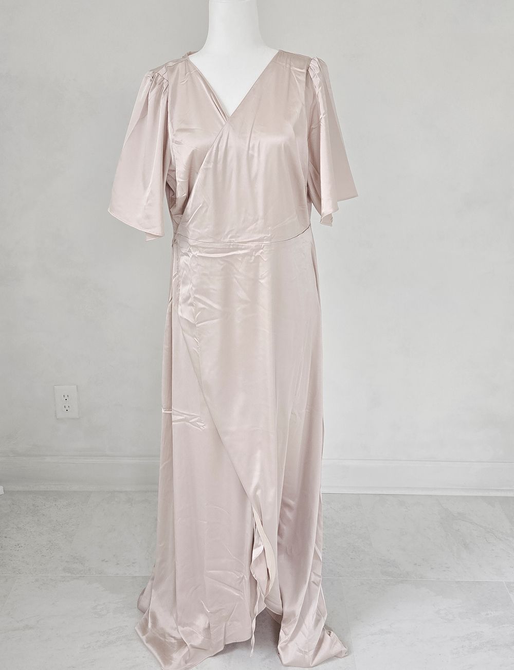 Elegant champagne-colored satin maxi dress with flutter sleeves and wrap-style skirt design.