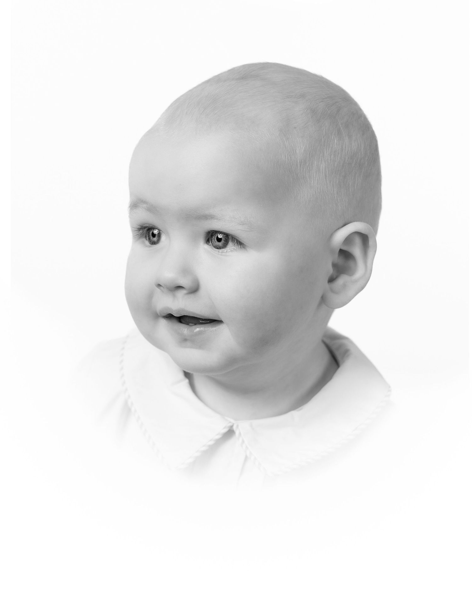 Three profile views of a smiling baby with bright blue eyes wearing a white outfit against a white background.
