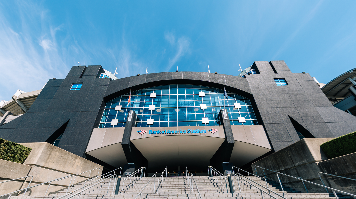 Charlotte FC Bank of America Stadium exterior featuring modern dark architecture and blue glass facade under clear blue sky.