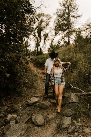 Two people hiking along a rocky forest trail during a summer adventure.