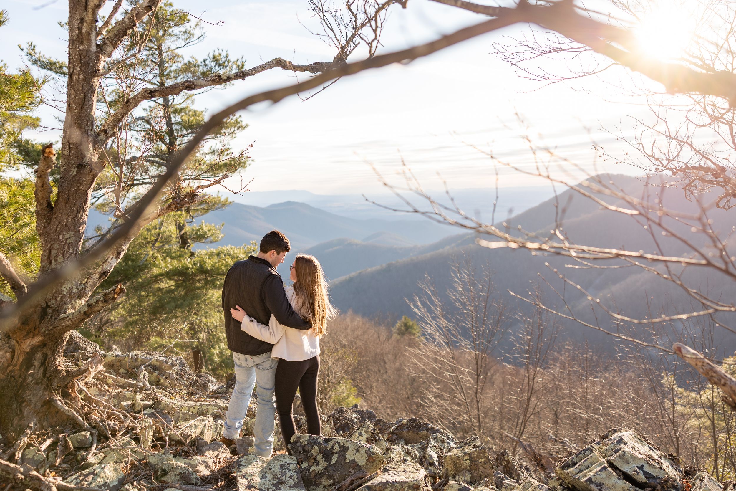 Hikers explore a scenic mountain trail surrounded by autumn trees during sunset in the wilderness.