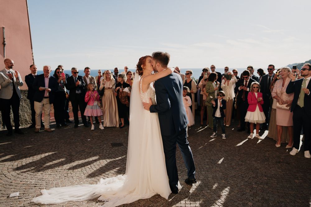 il bacio degli sposi in mezzo agli invitati fuori dalla chiesa di san pietro nel parasio di imperia