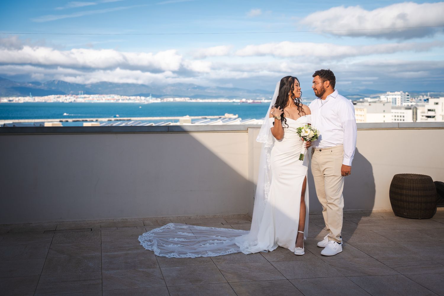 Bride and groom smile on rooftop of Elliot Hotel before wedding In Gibraltar