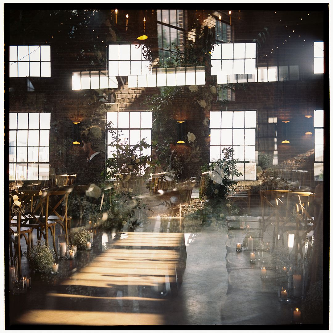 A dark industrial space filled with hazy smoke and dramatic beams of sunlight streaming through large windows.