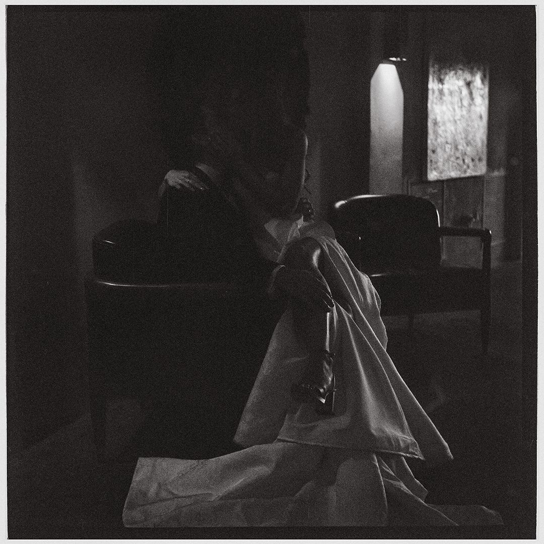 Black and white photograph shows a dimly lit interior scene with multiple panels depicting a figure in shadow.