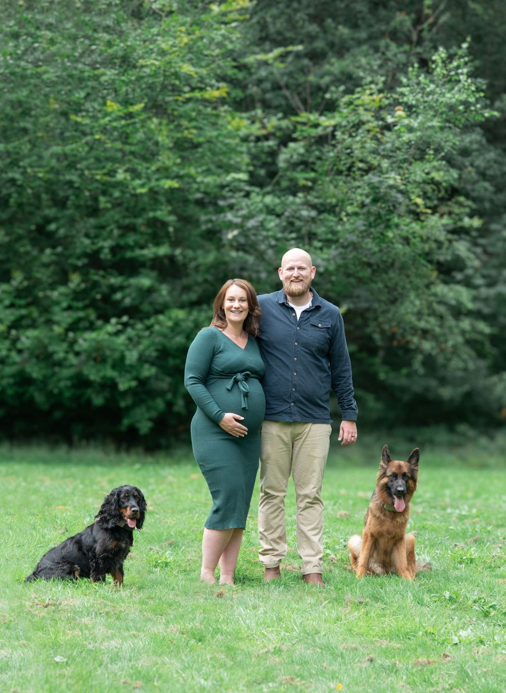 A pregnant woman and her husband stand together with their two dogs at Otley chevin park in West Yorkshire.
