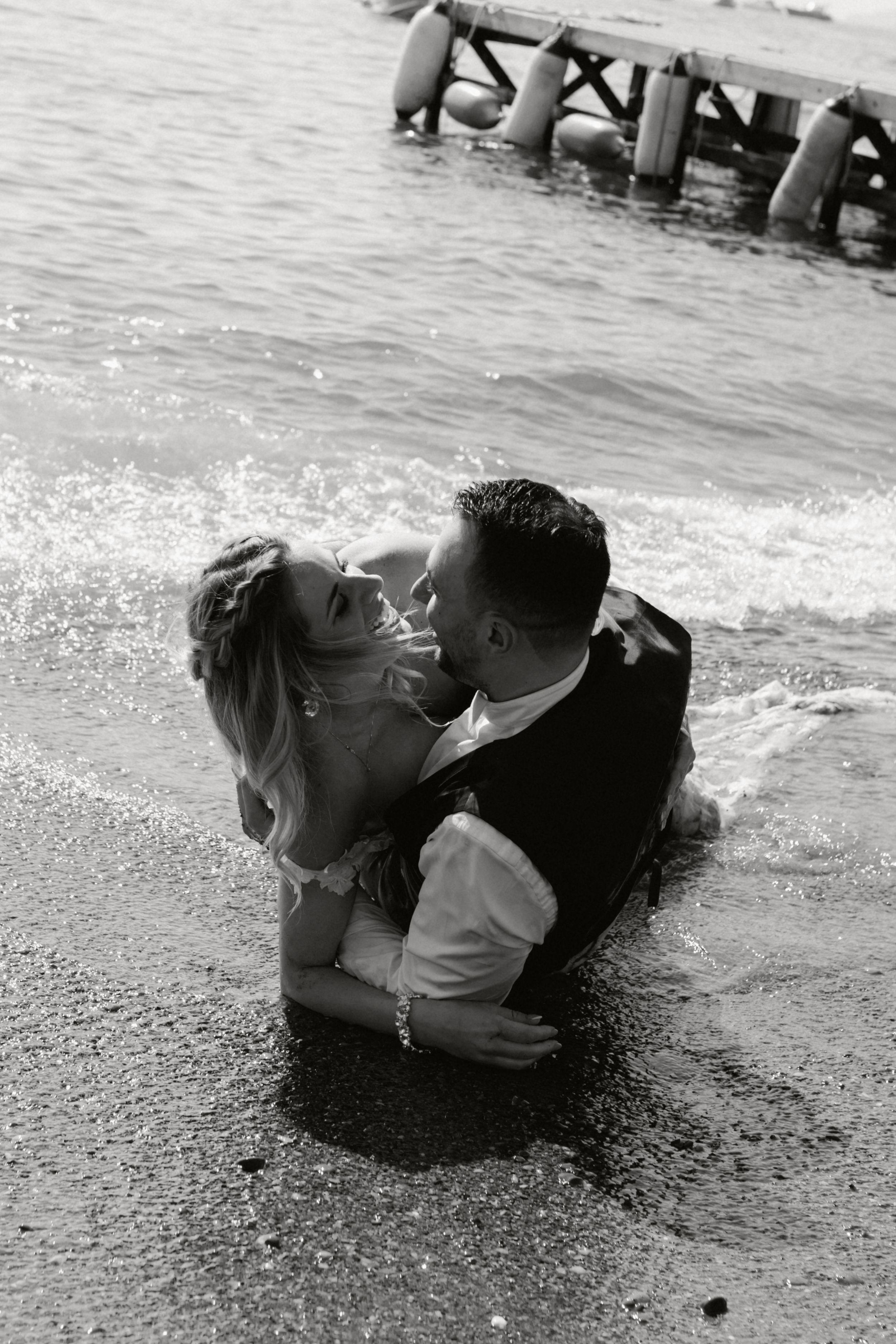 A romantic black and white sequence of a couple lying on a beach as waves wash over them.