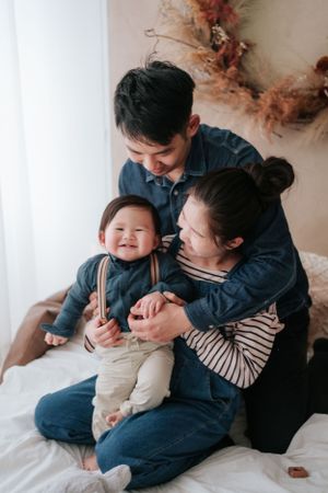 Candid family moment captured on a white bed with natural lighting在自然光下，一家人躺在白色床上，溫馨的一刻被鏡頭捕捉下來。