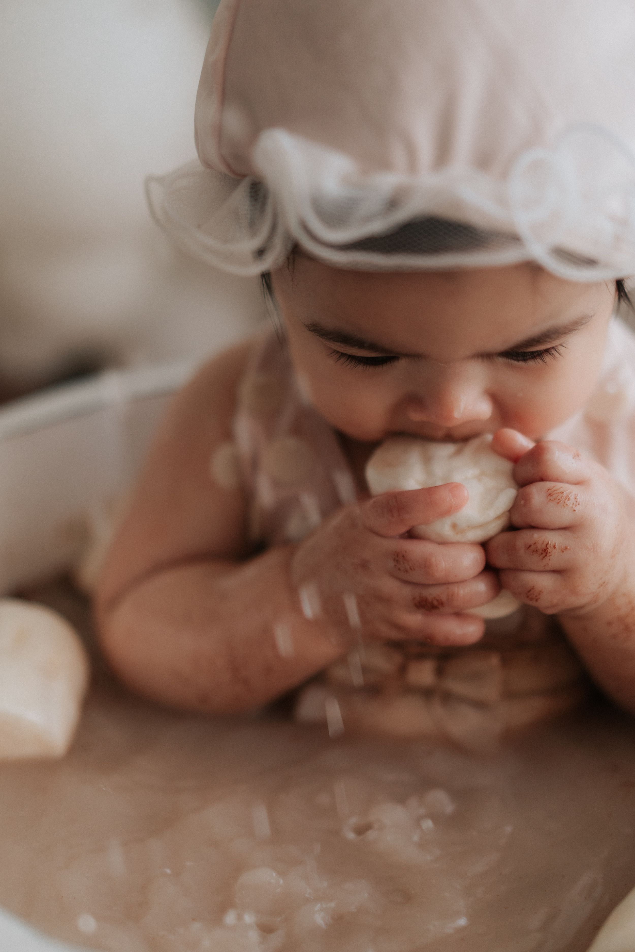 Close-up of hands covered in white frosting during a smash cake photoshoot.在拍攝蛋糕砸臉照時，特寫鏡頭捕捉到沾滿白色糖霜的雙手。