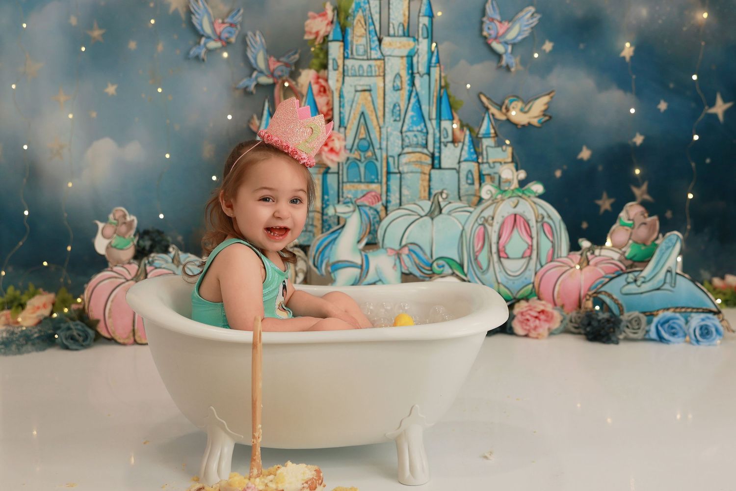 A whimsical cake smash photo session with twinkling lights, blue and pink decor, and a joyful expression.
