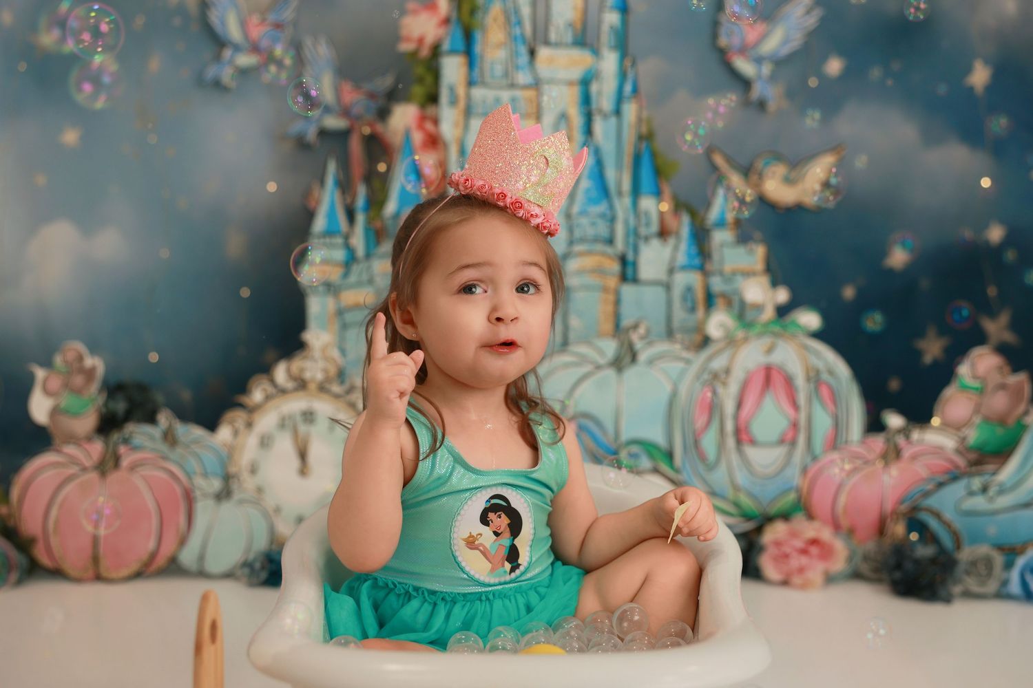 A princess-themed photo setup with a castle backdrop, pink pumpkins, and teal and pink decorations for a magical portrait.