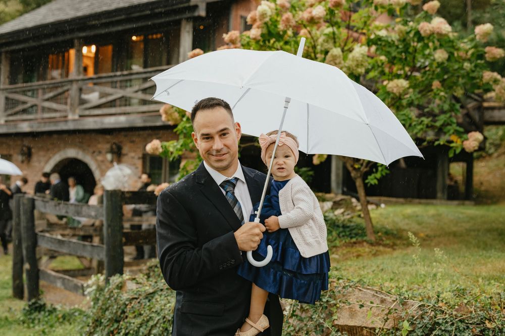 Wedding couple shares an intimate moment under a white umbrella in a lush garden setting.
