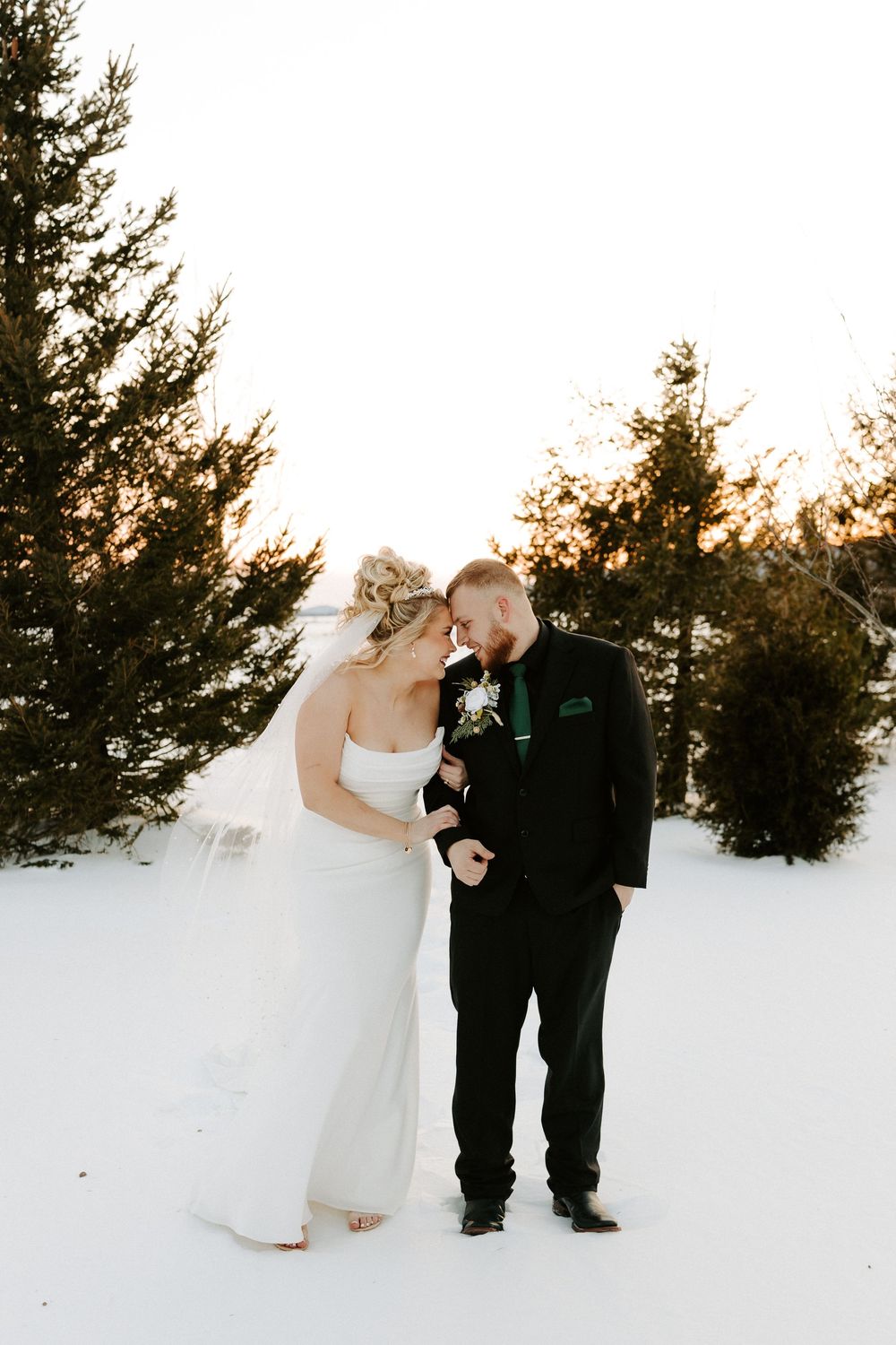Newlyweds share an intimate forehead touch in a serene snowy winter wedding setting.
