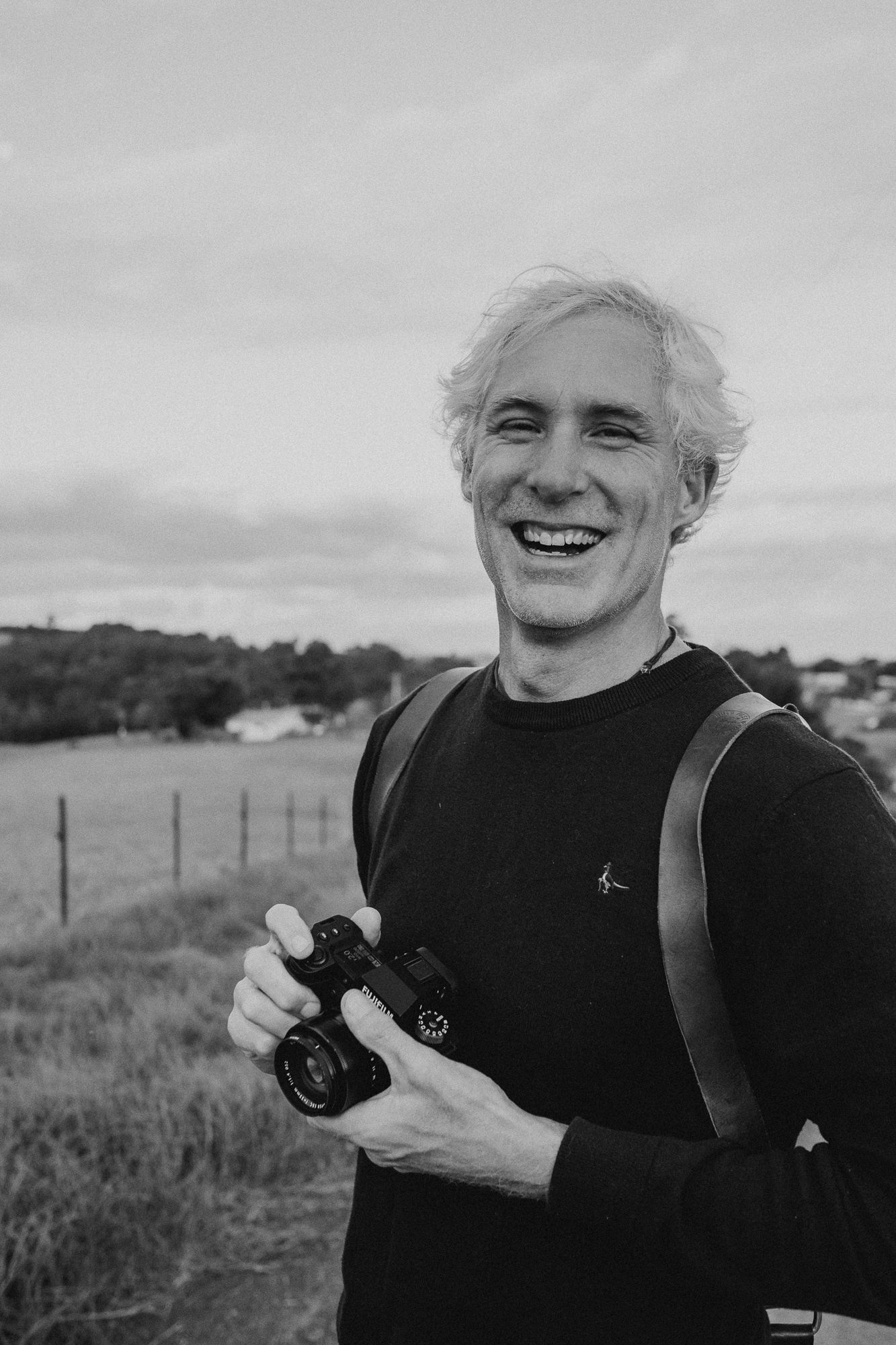 Black and white photo sequence showing a joyful expression and camera against a rural landscape background.