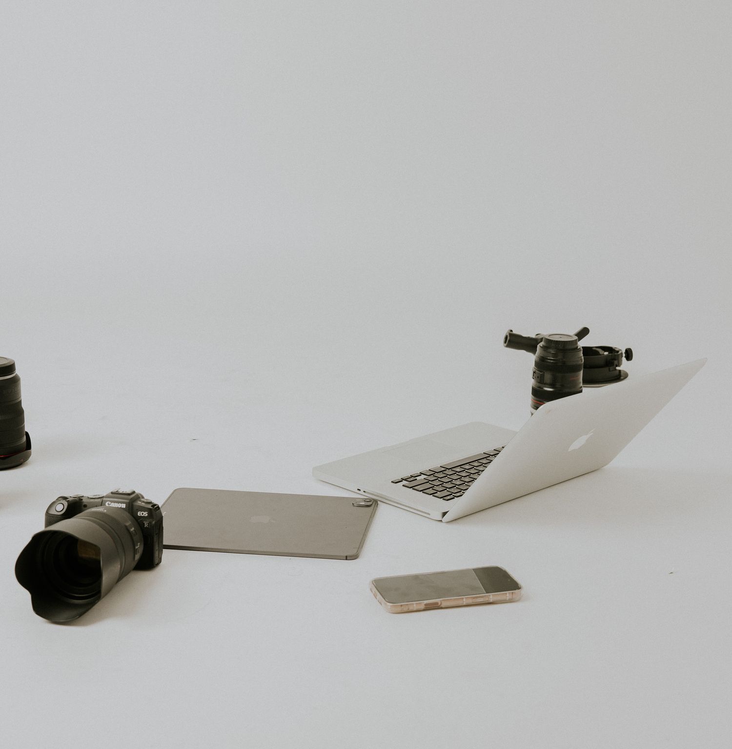 A photographer lying on the floor using a laptop with camera equipment nearby in a studio setting.
