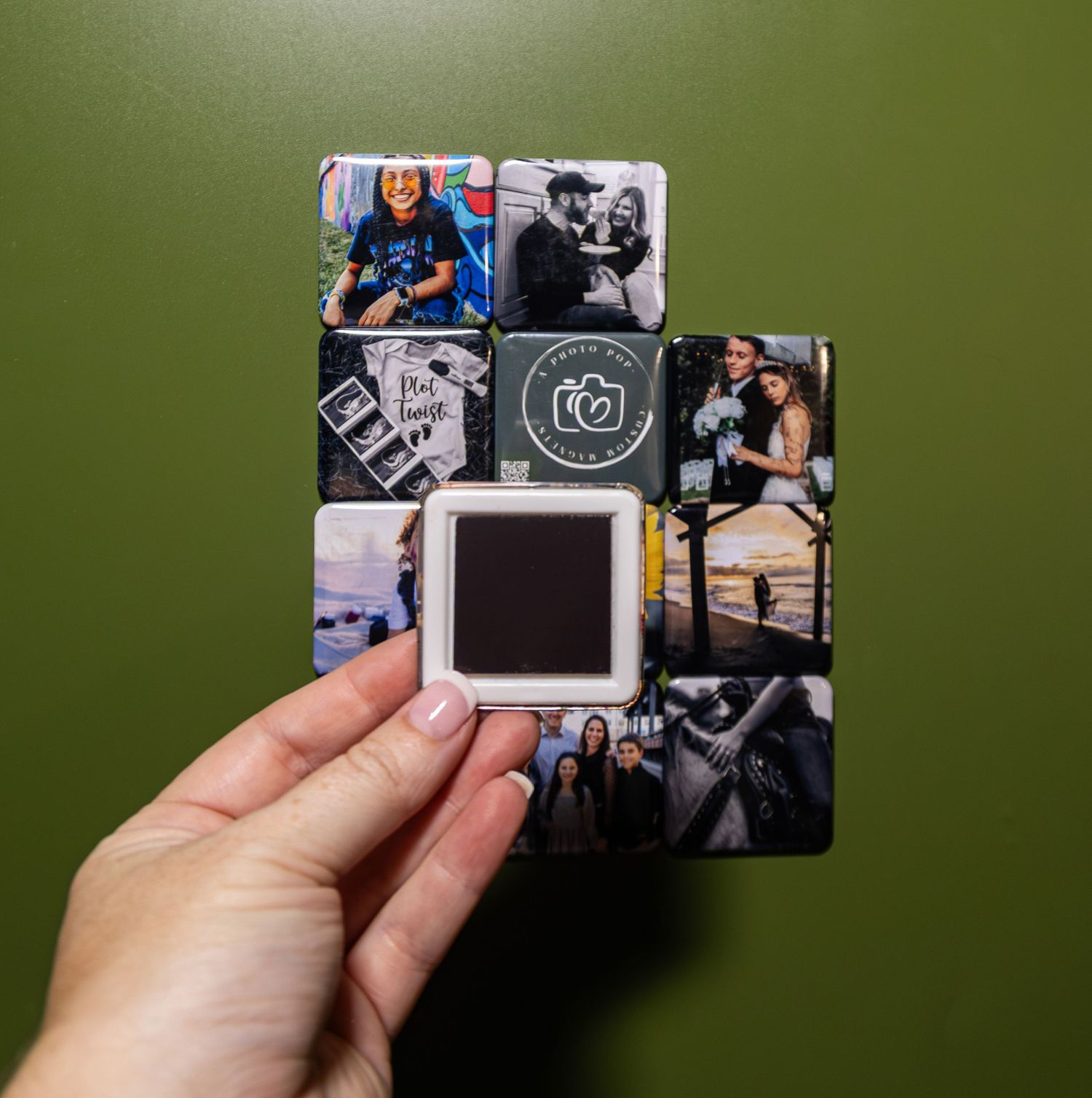 Hand holding a black credit card with photo collage design against green background.
