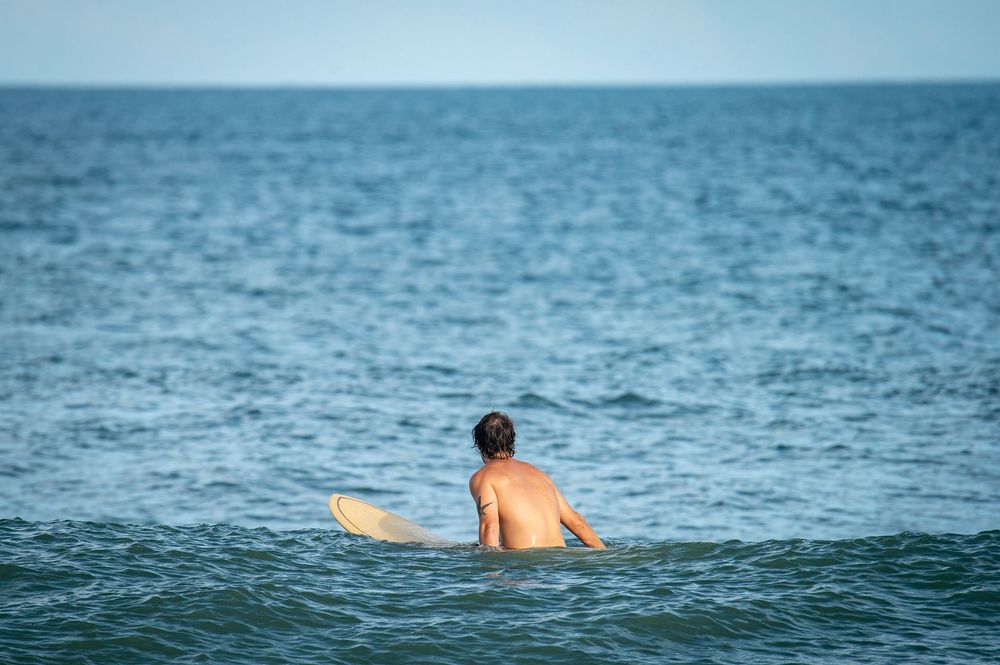 A person swimming and surfing in the vast blue ocean on a bright sunny day.