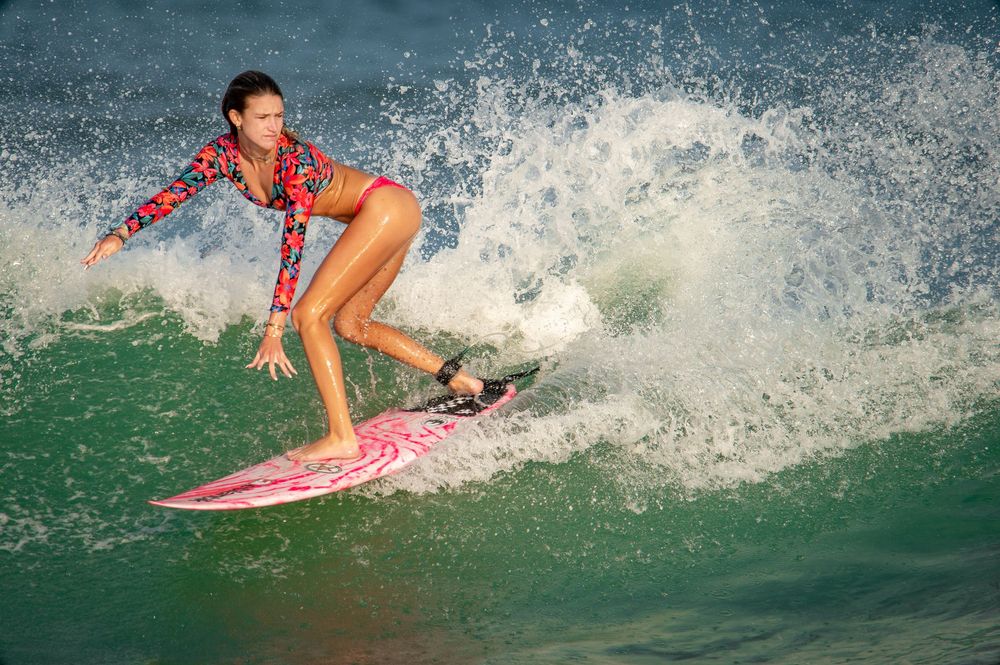 A surfer rides a wave while performing a cutback maneuver, creating a dramatic splash of ocean spray.