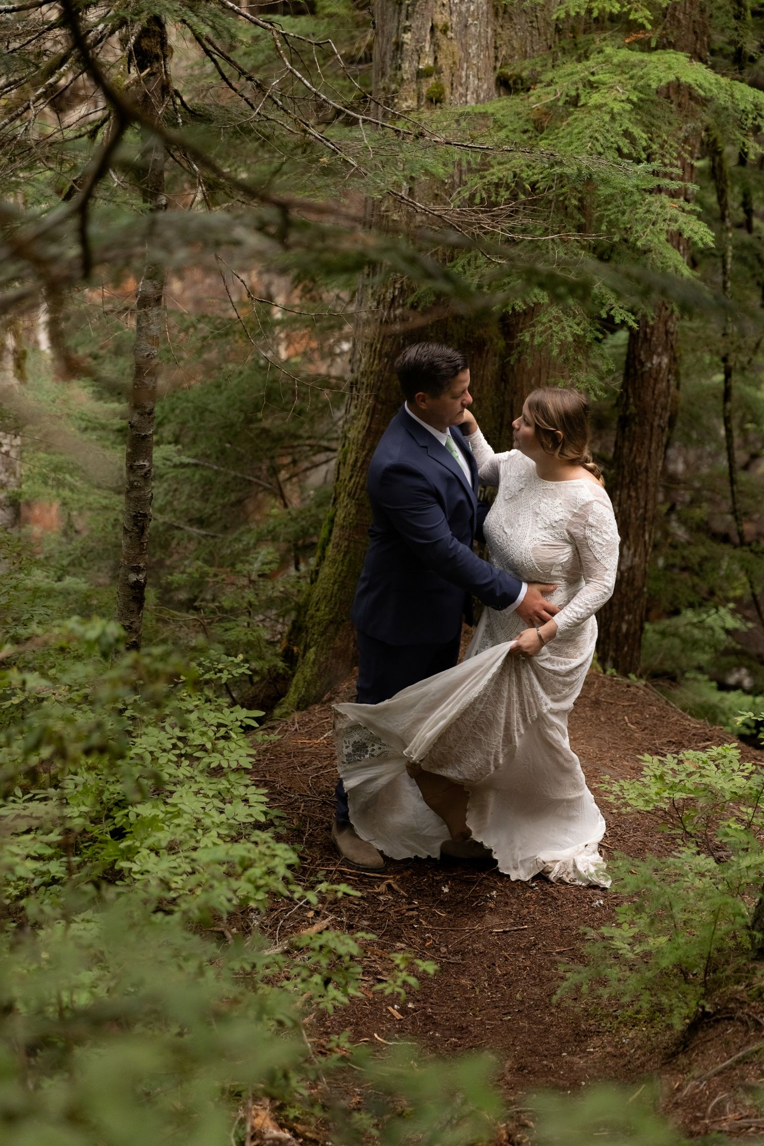 Erin and Charlie dance in the forest, framed by lush green foliage, during their Washington elopement.