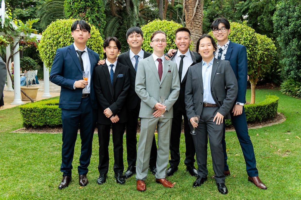 Sydney Event Photography - A group in formal attire poses for a formal photo in a manicured garden setting.