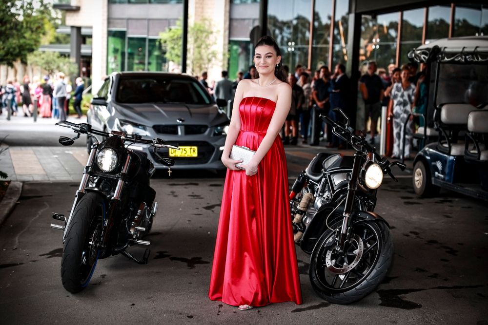 Sydney Event Photography - A woman in a red formal gown poses between two motorcycles under an urban overhang.