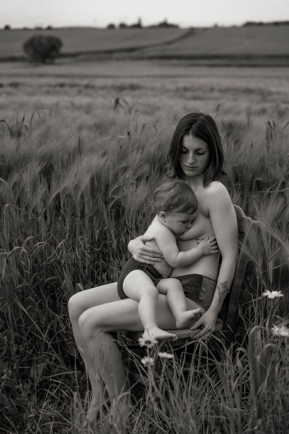 Black and white photo series of mother and child bonding together while sitting in a grassy meadow field.