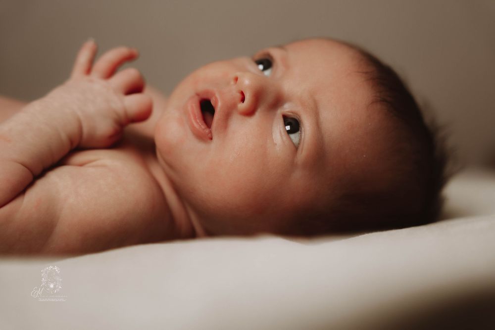 A series of connected photos showing a baby lying on their back in various peaceful poses on white bedding.