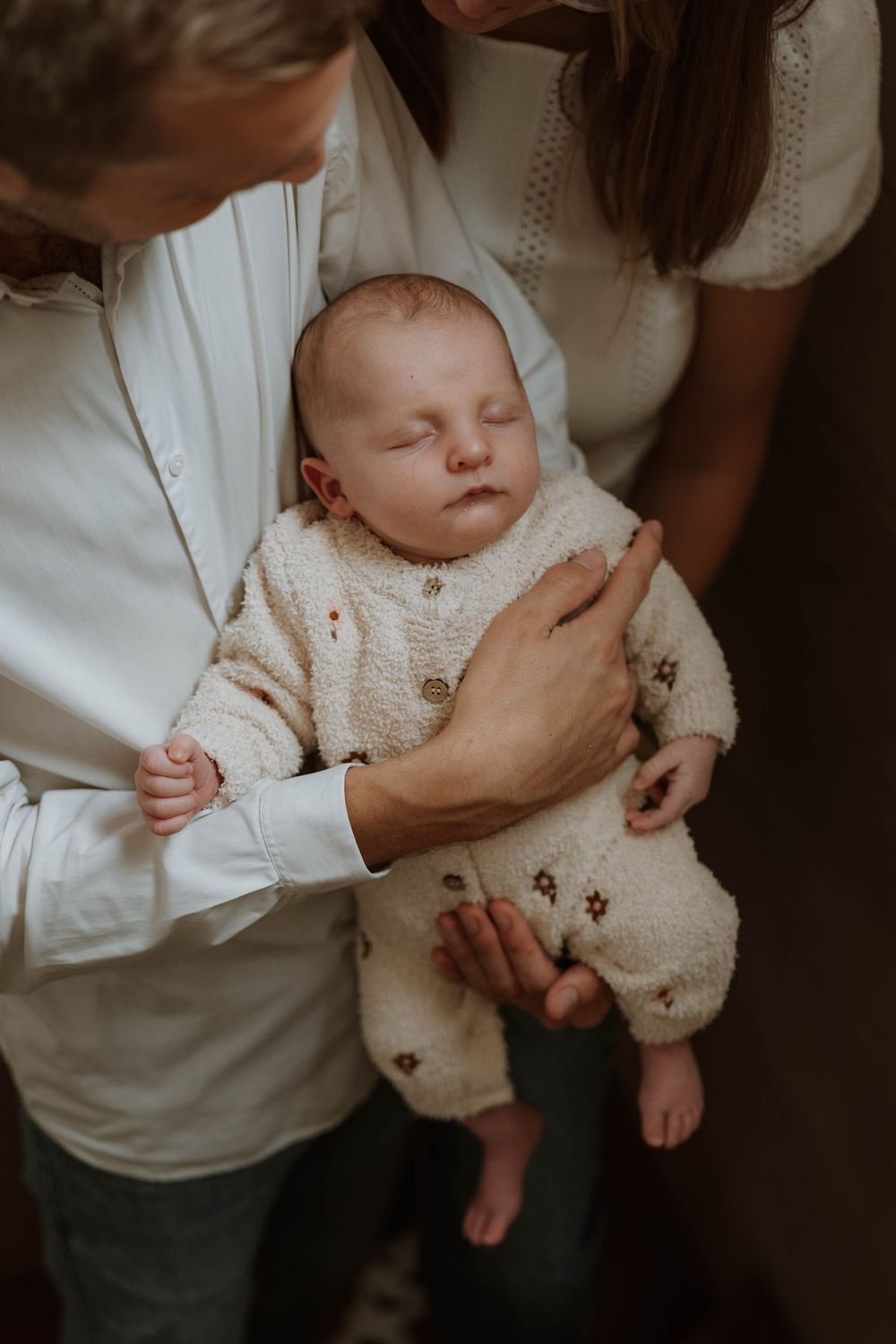 A series of intimate photos showing a baby in a white sweater being held and cradled in someone's arms.