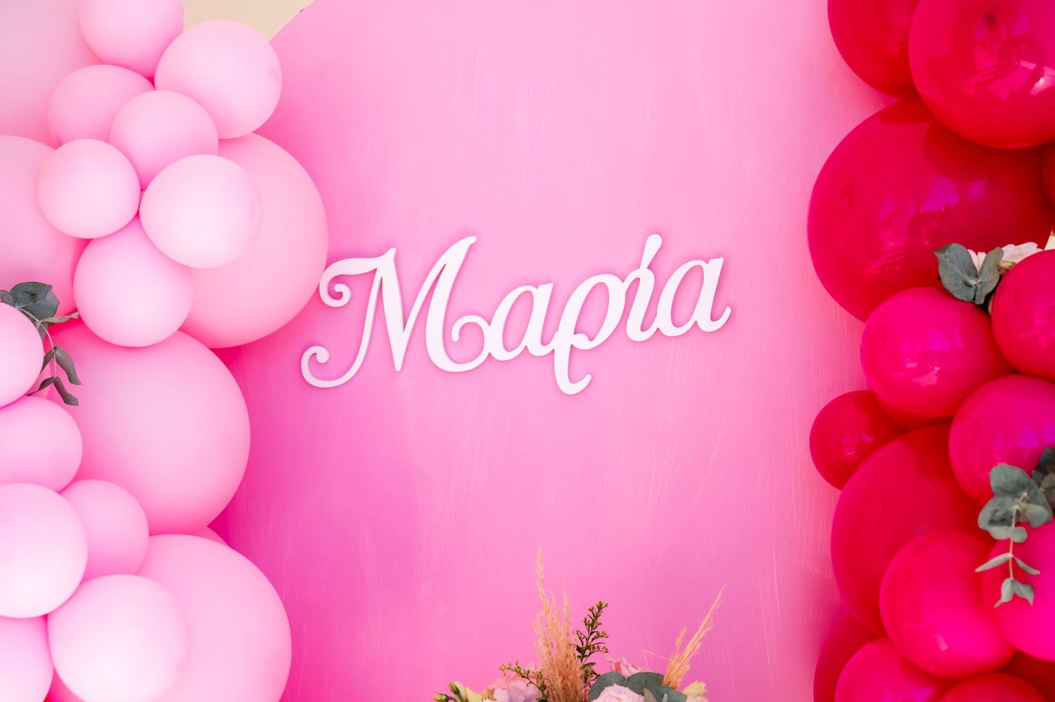 Pink balloon decoration setup with Maria text against gradient background.