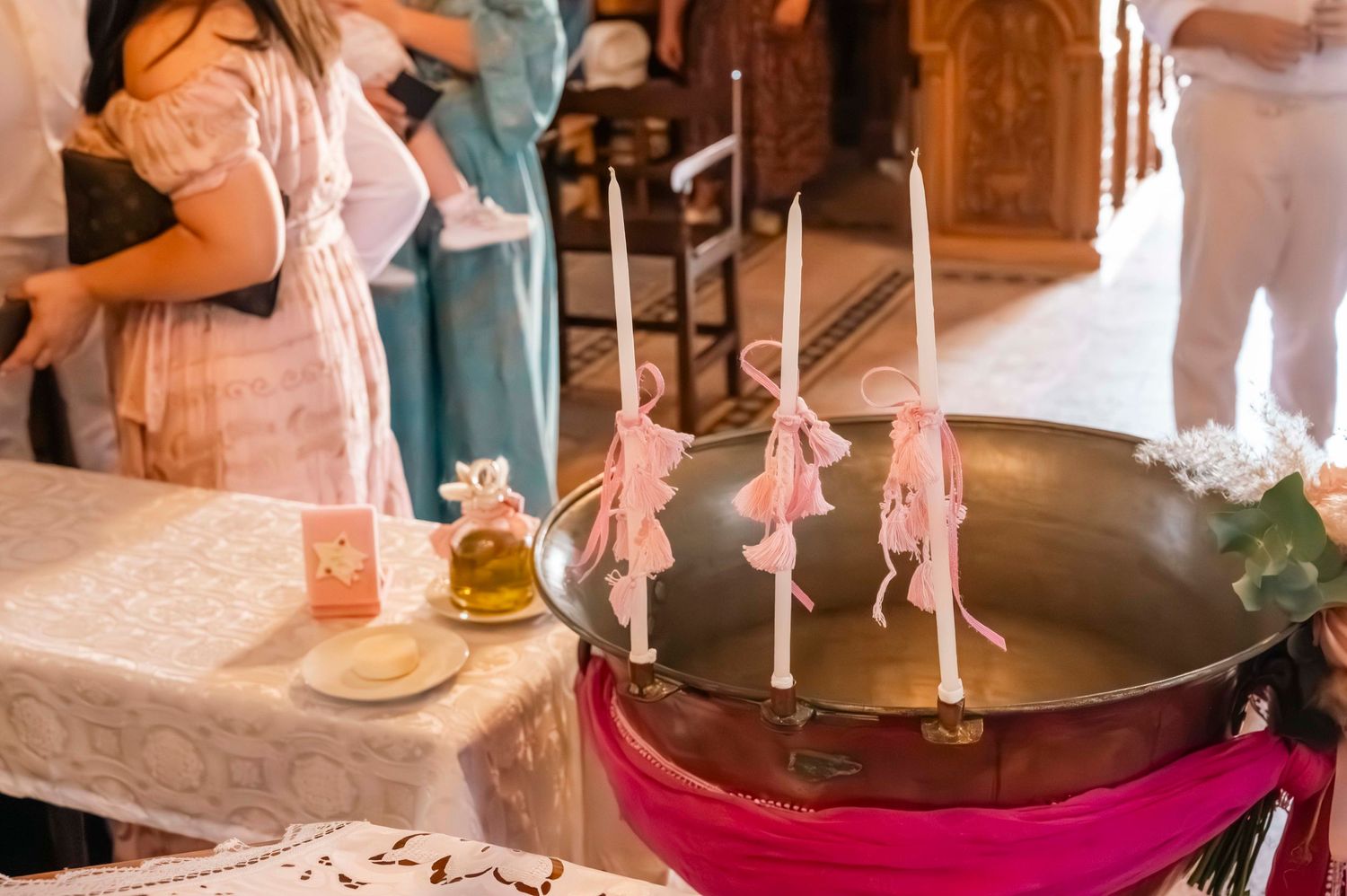 Pink decorated candles arranged around a dark basin during a religious ceremony.