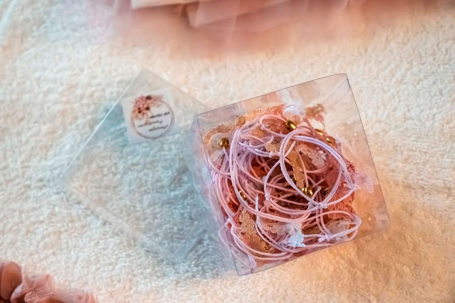 Pink ribbons and decorative elements in a clear box with delicate lace details.