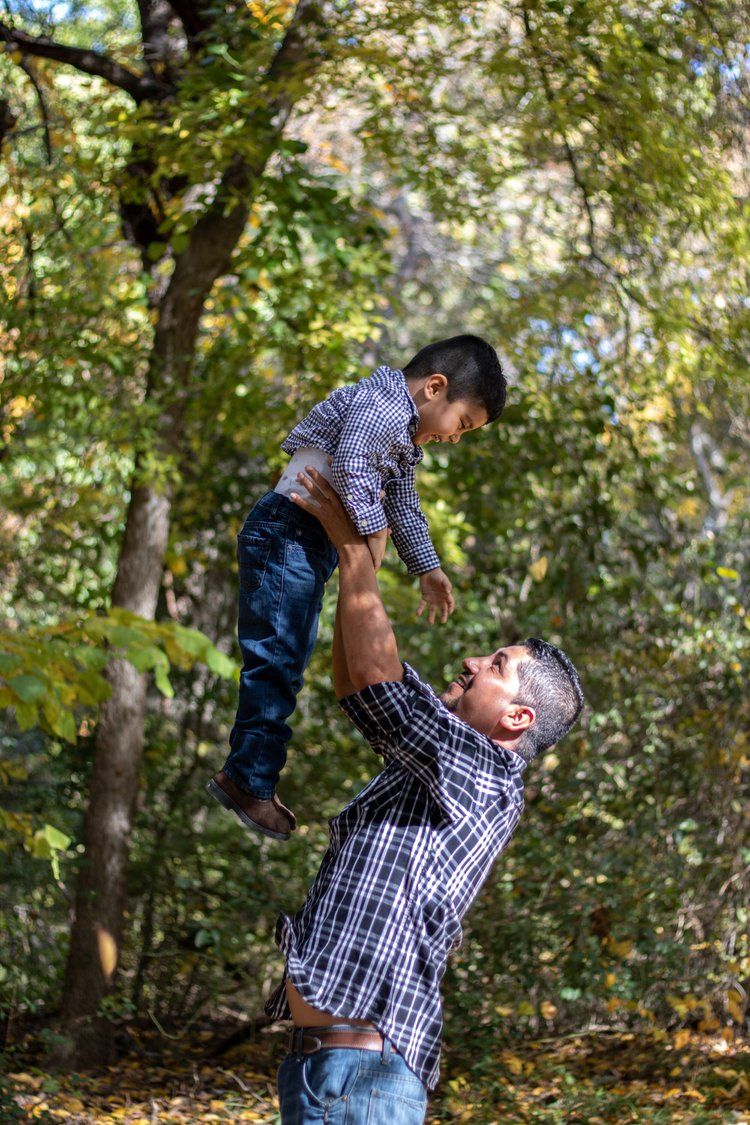 Playful sequence of parent tossing child in the air among autumn trees.