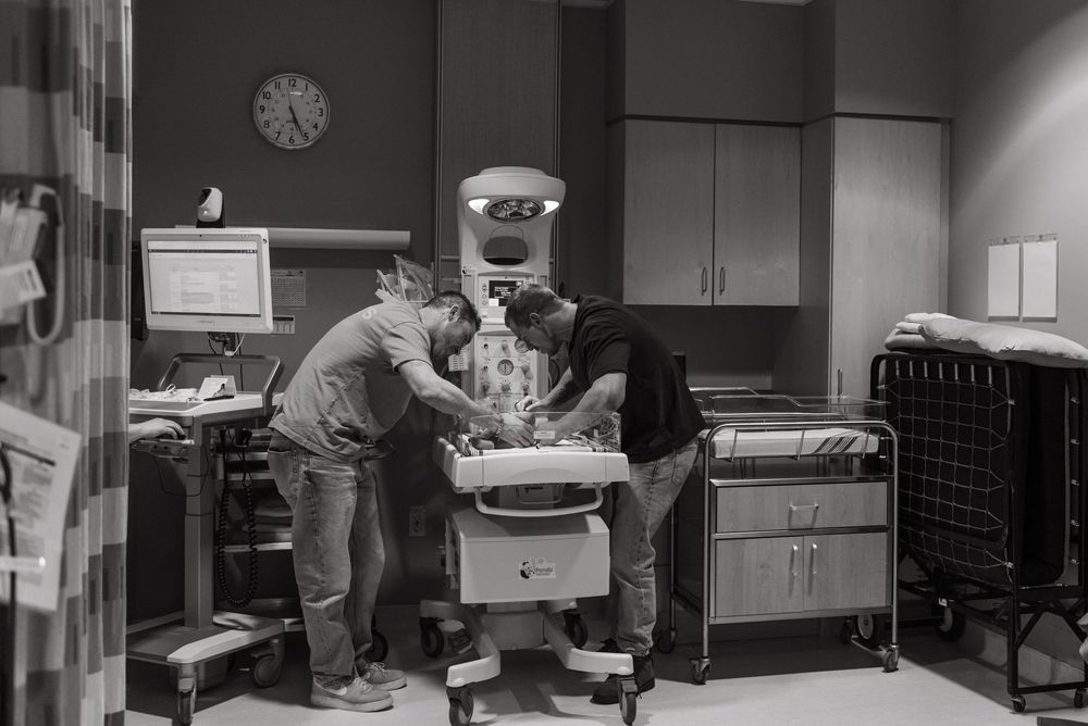 A historical black and white photo of hospital nurses tending to newborns in a nursery ward.